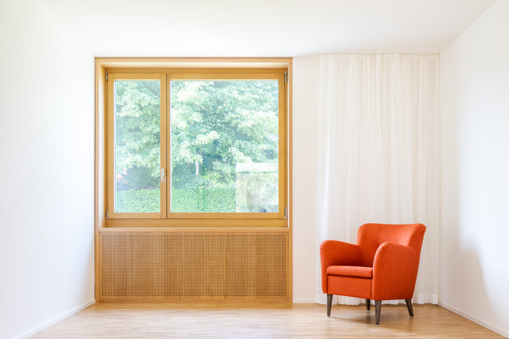 Fenster sind in Eiche umrahmt. Das Brüstungspanel ist gelocht und wird zur Verbesserung der Raumakustik genutzt.