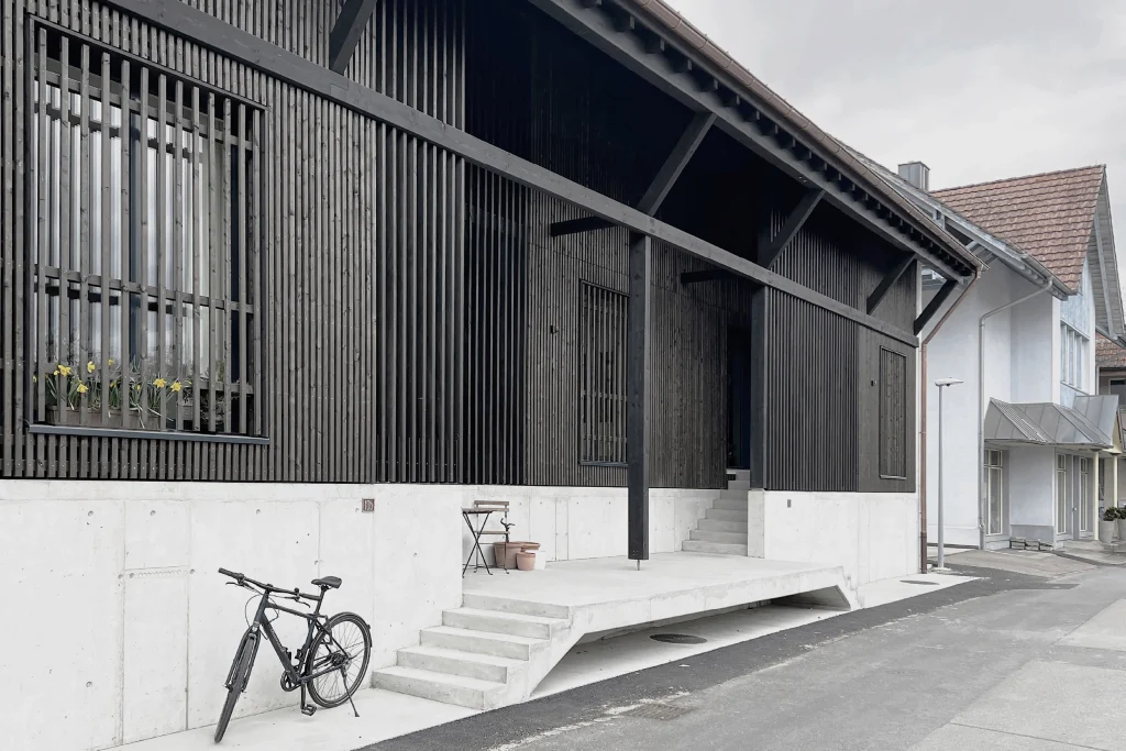 Ansicht der Remise, Alle Gebäude haben zum Hochwasserschutz einen Betonsockel der sich als Teil der Fassadengestaltung sichtbar abzeichnet.