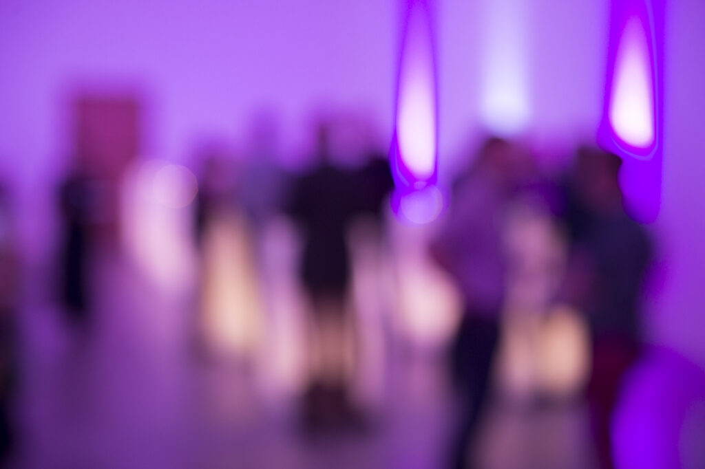 Im Kultur- und Kongresshaus Aarau feiert Metron sein 50jähriges Jubiläum. Stimmungsvoll in violettes Licht getaucht unterhalten sich Mitarbeitende und Gäste an der Bar. Der Metron Förderpreis unterstützt zukunftsgerichtete Kulturprojekte.